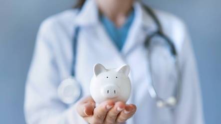 Doctor holding small piggy bank